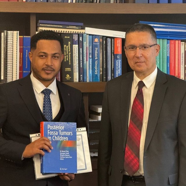 Dr. Surafel Mekonnen with Professor M. Memet Özek at Acıbadem University, holding Posterior Fossa Tumors in Children